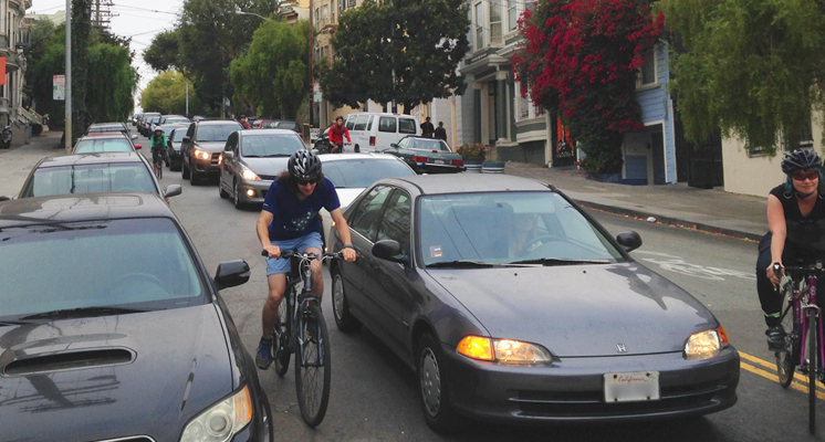 A common sight on Page Street, as people on bikes are forced to squeeze between cars.