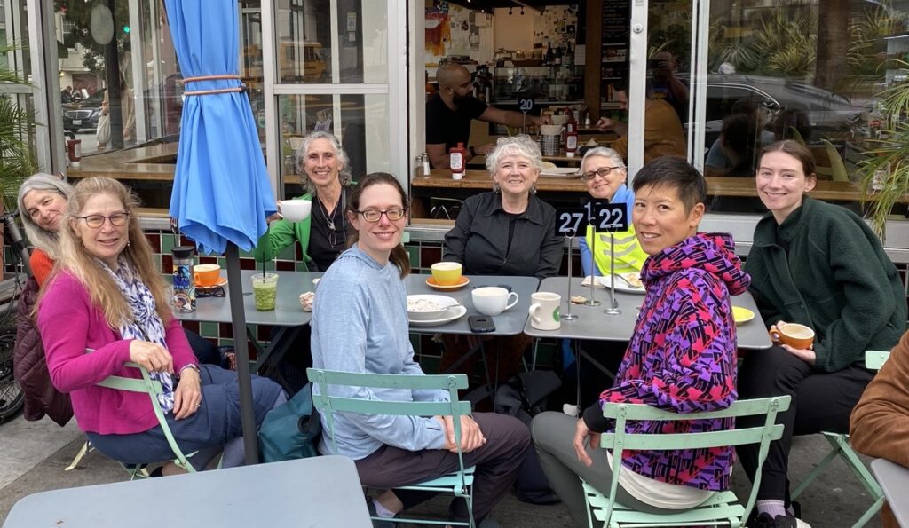 8 people around a table at an outdoor cafe.