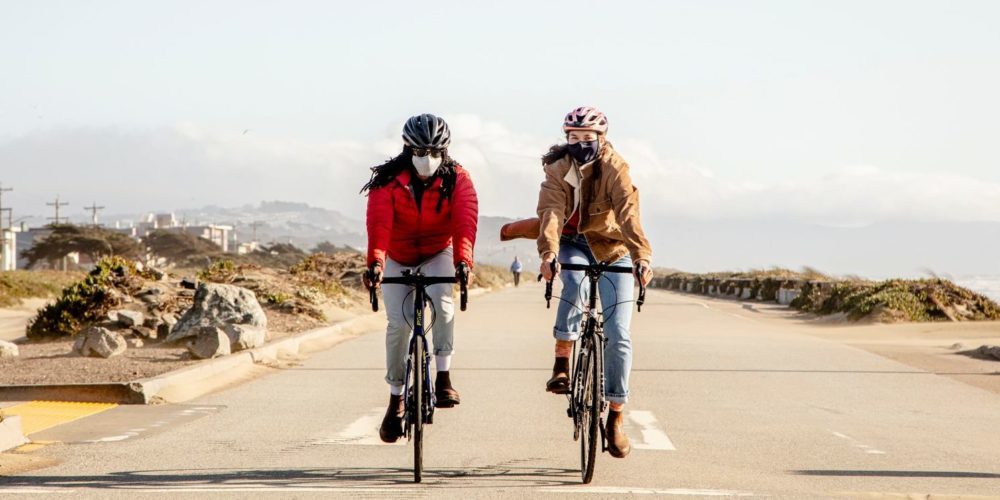 Photo of two people biking next to each other on car-free space by the beach in SF