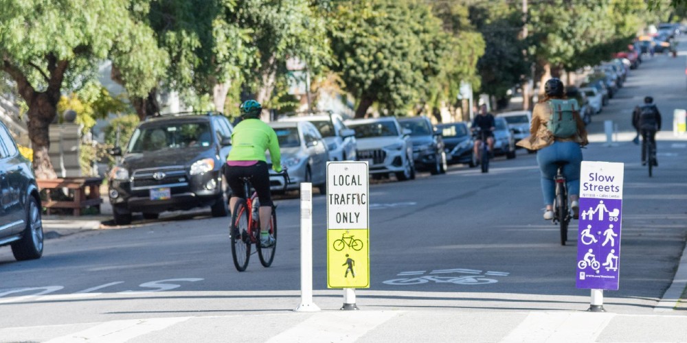 photo from the SFMTA of two people biking on a slow street. signs that say local traffic only, slow street.
