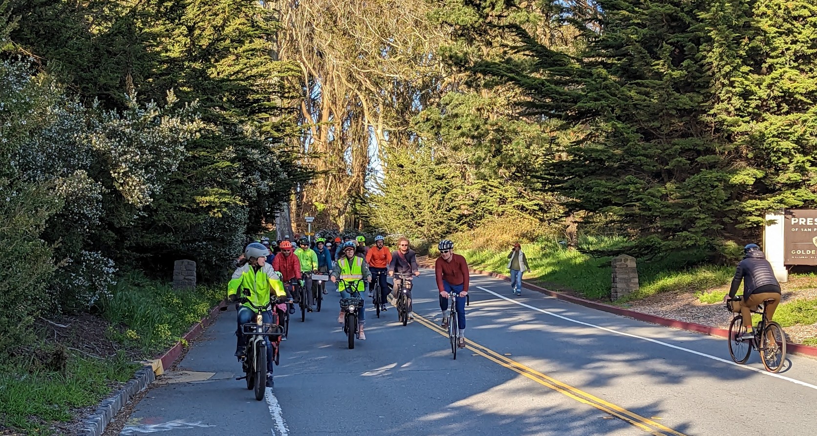 Group of people riding bikes through Presidio Gate.