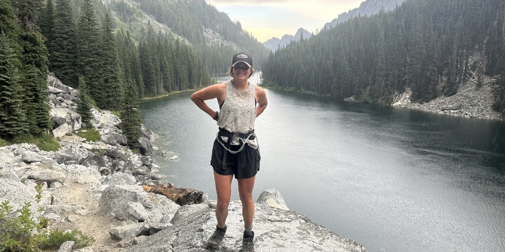 A woman stands in front of a river and forest