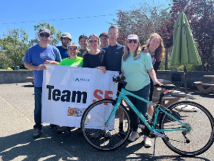 A group of people, one with a bike, hold a banner that reads "Team SF"