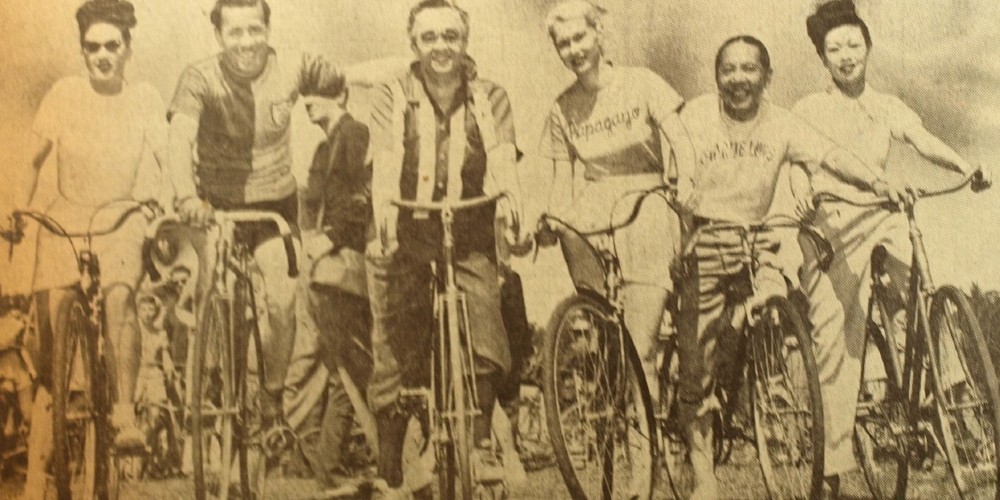 a historic, black and white photo of a group of people on bikes posing for a photo